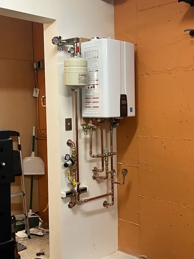 Plumbing technician inspecting water heater connections in Manistee